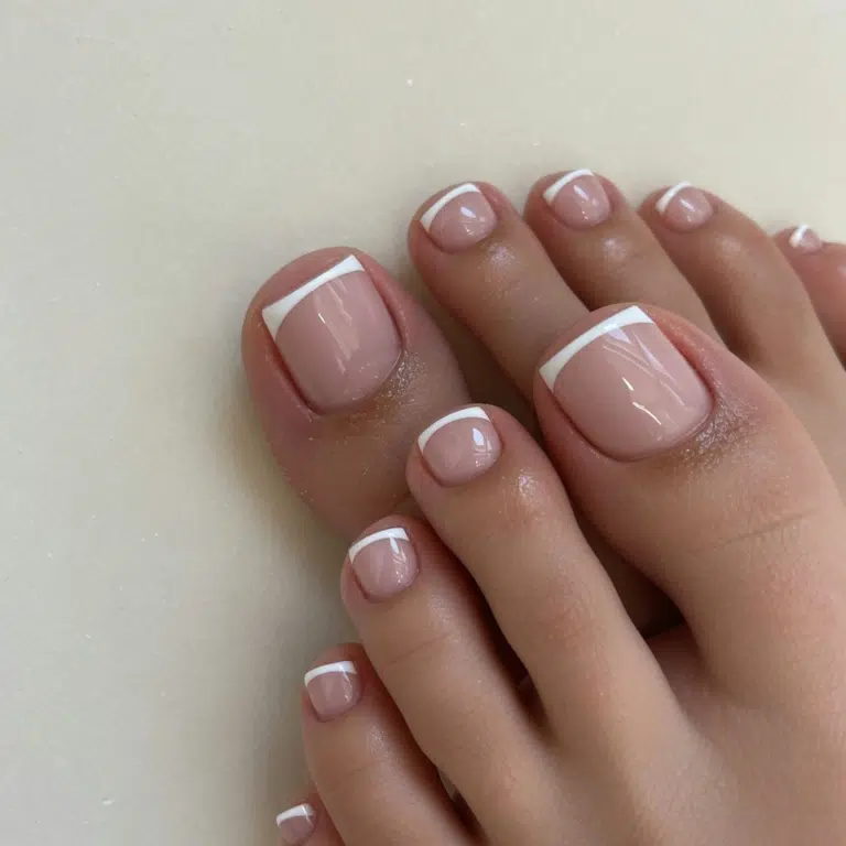 Finished at-home pedicure with a glossy nude base and crisp white tips.