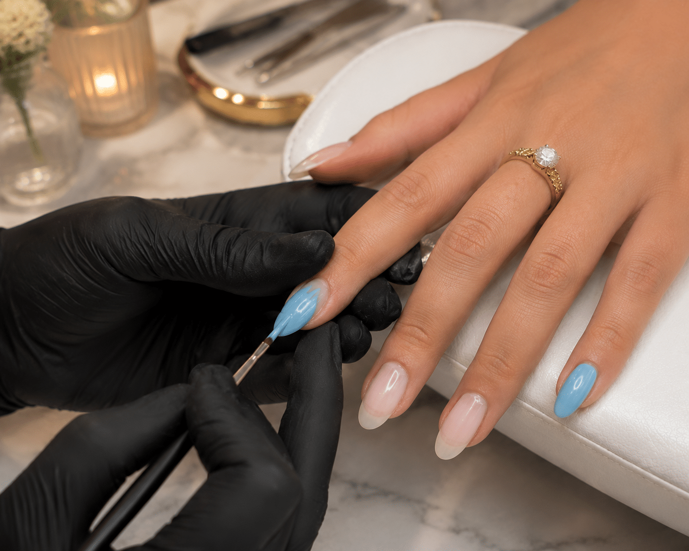 Nail technician applying light blue gel polish during a summer manicure