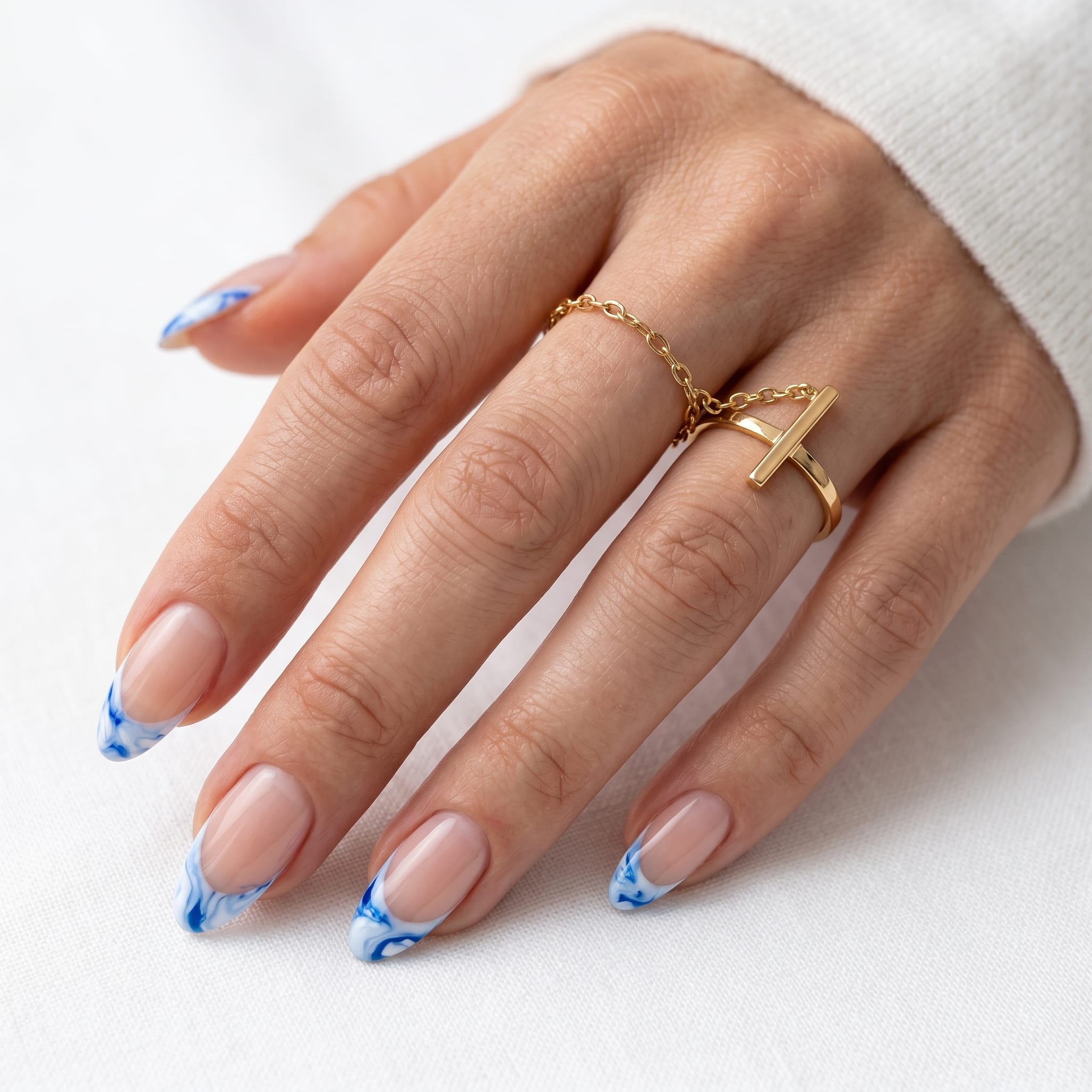 Nude almond nails with fine bright blue French tips