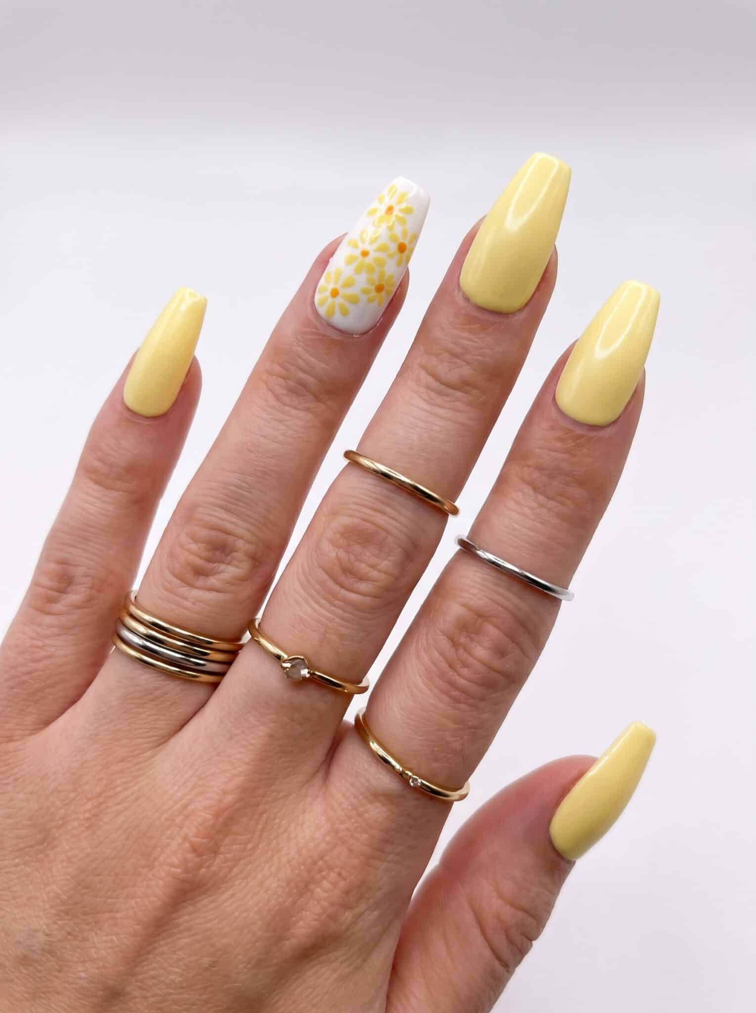 Butter yellow almond nails with a glitter and tiny floral accent nail