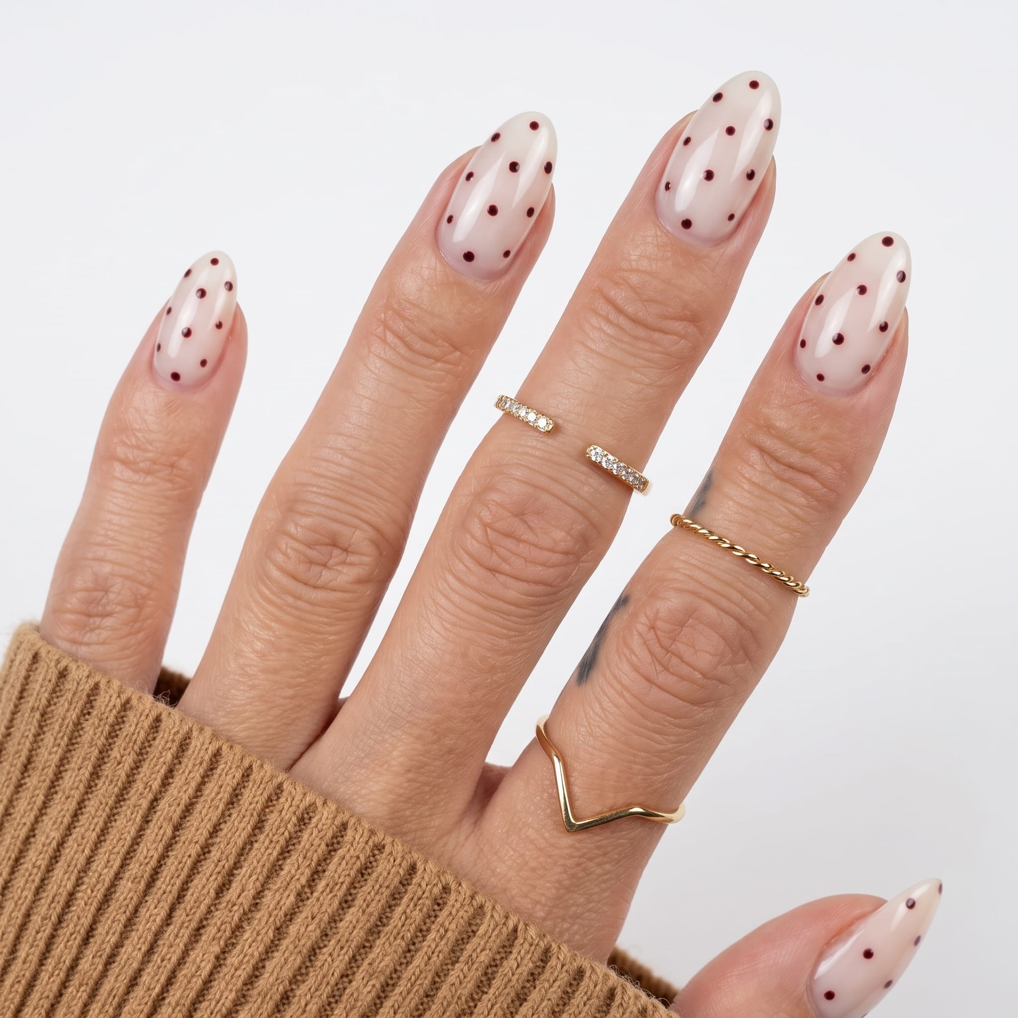 Nude almond nails with dense pastel pink blue yellow and mint polka dots