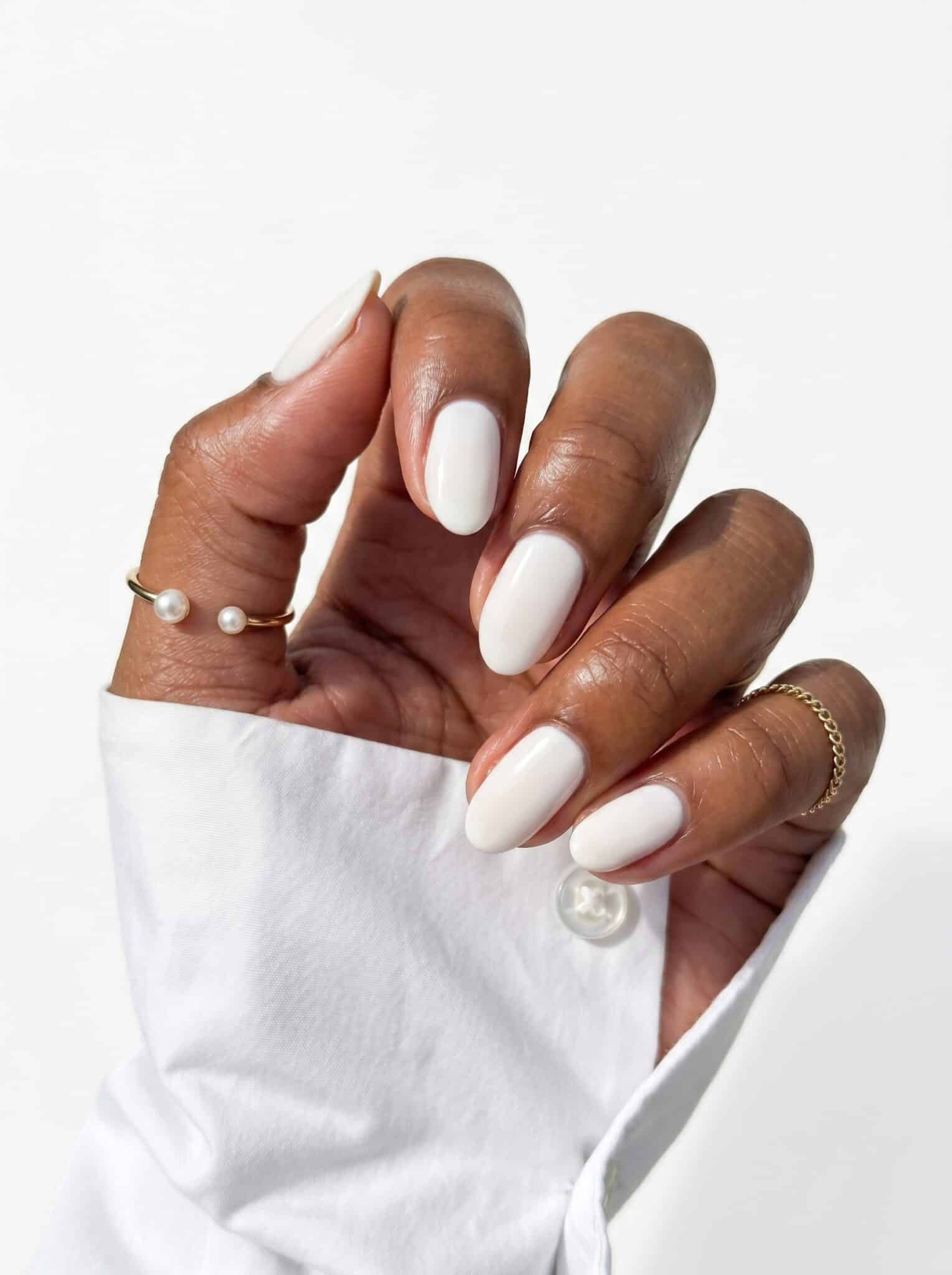 Soft pink nails with white French tip details and small crystal accents