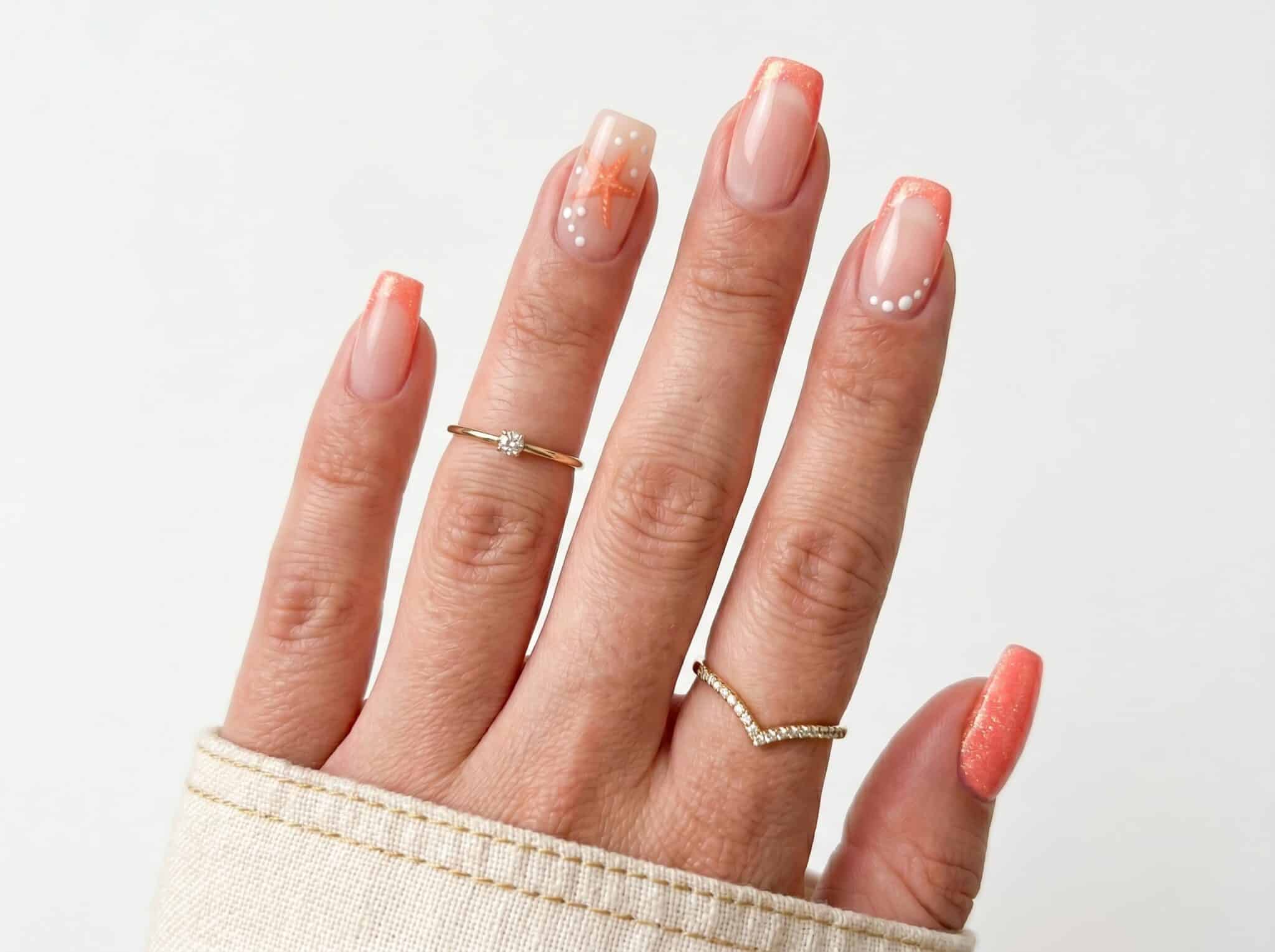 Sheer nude nails with soft coral accents and a glossy finish