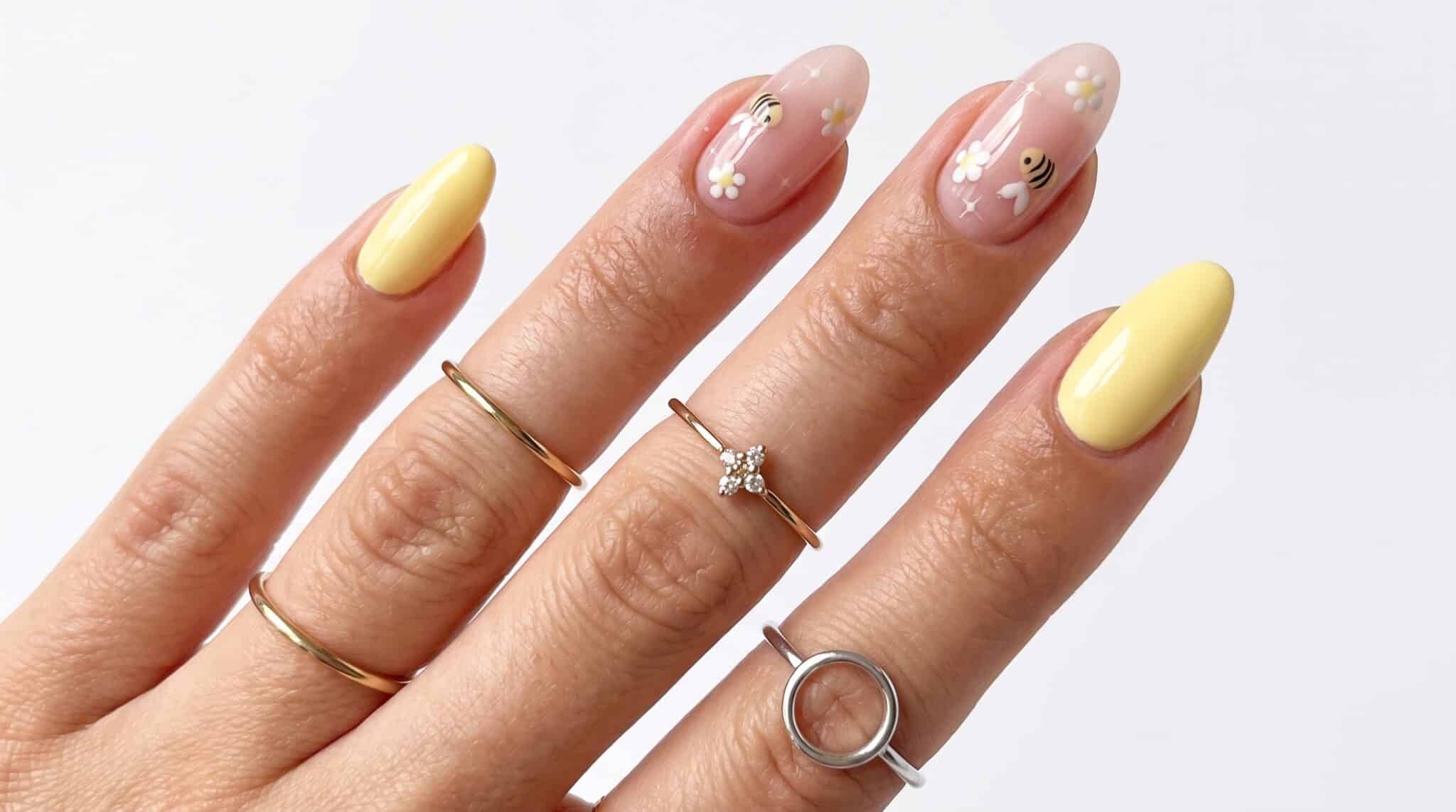 Glossy bright yellow almond nails with soft pink accent details