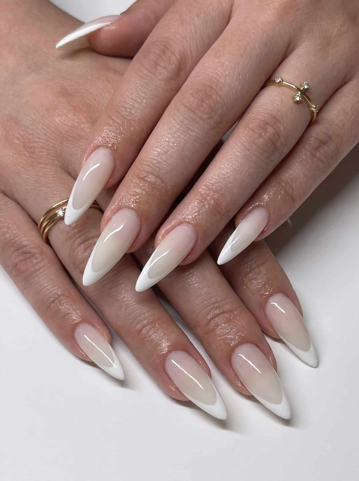 Nude nails with white French tips and delicate white floral accents