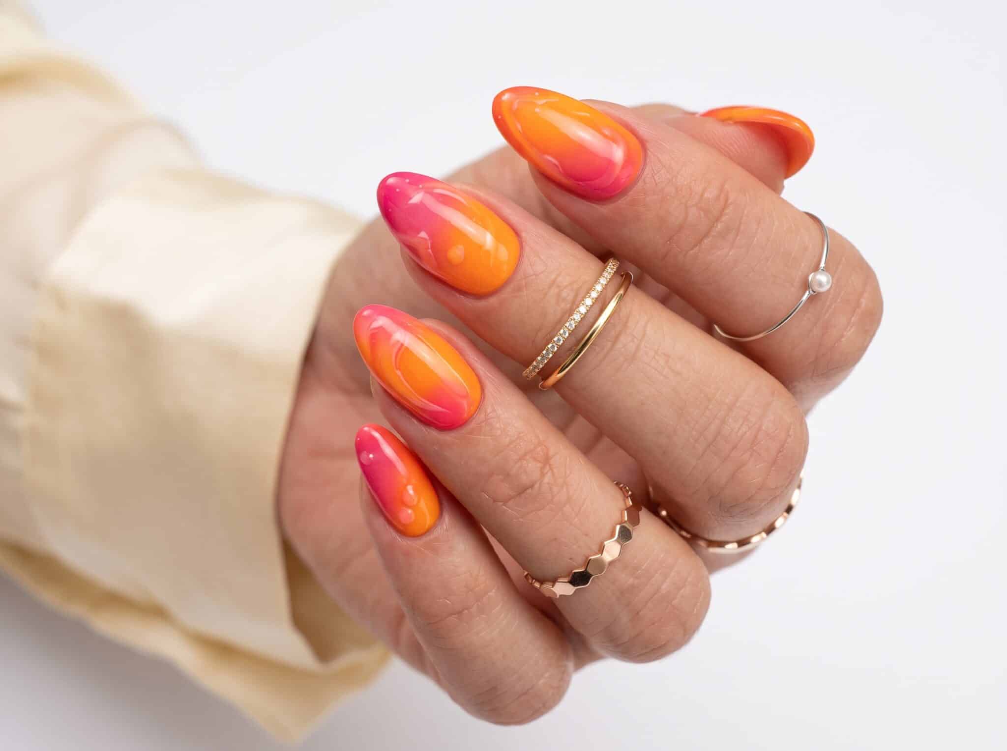 Hot pink and orange glossy swirl nails with a bright summer finish