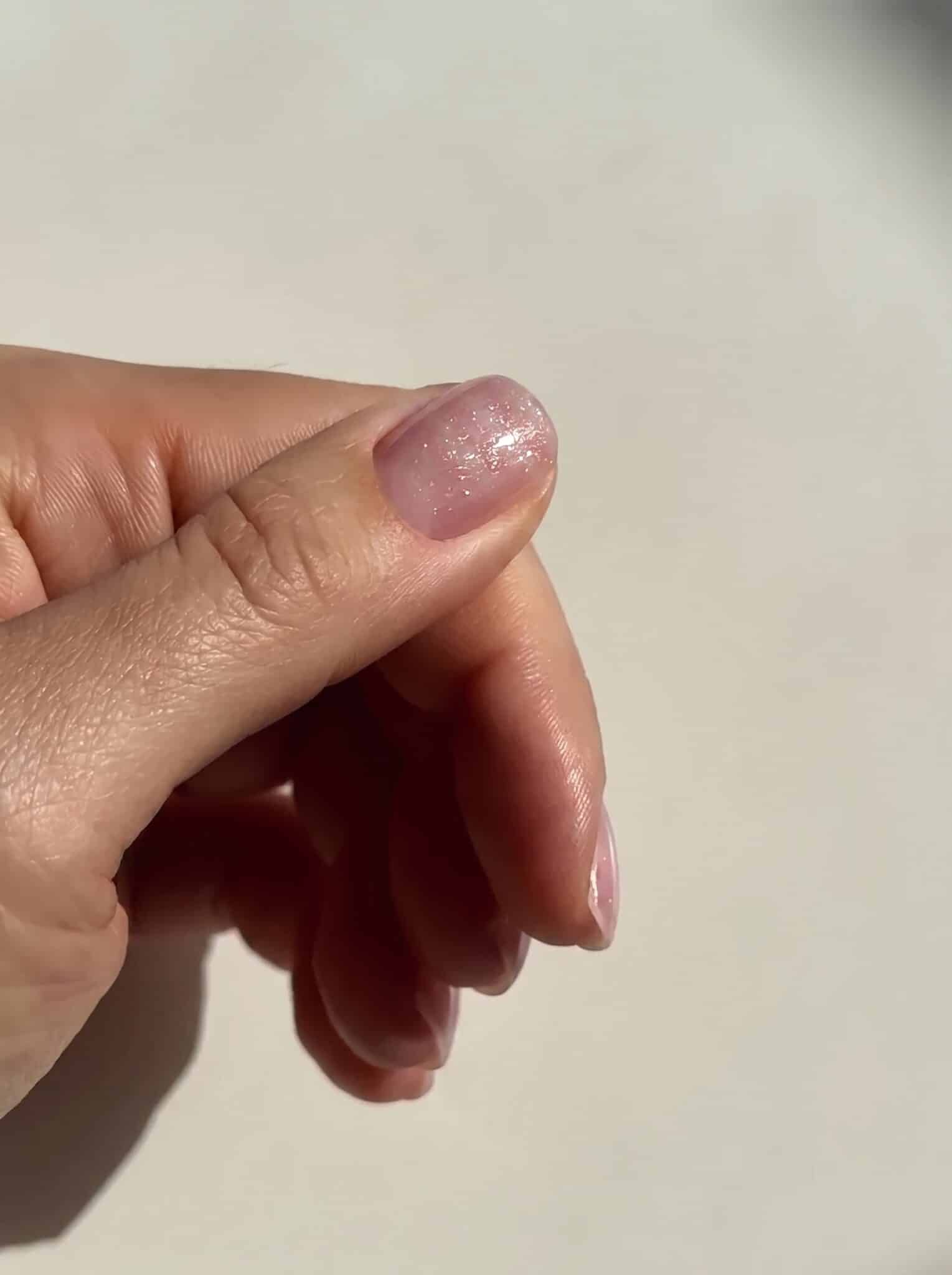 milky gemstone neutral nails with glossy pink base and rhinestone accents