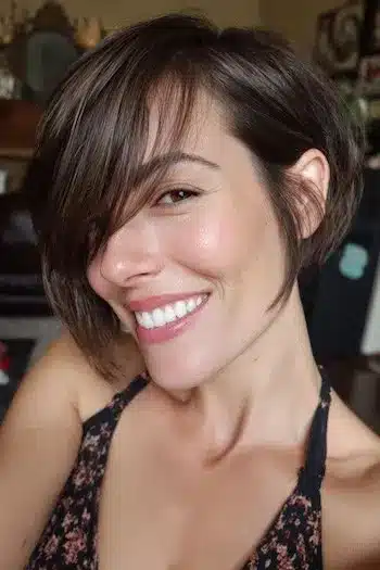 Brunette bixie with long side-swept bangs representing 31 Bixie Haircuts That Perfectly Blend Bob and Pixie Hairstyles