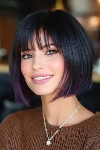 Blunt bob with piecey bangs and purple tips on a smiling woman